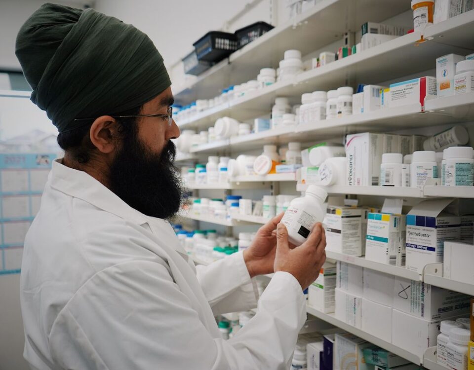 Pharmacist checking medicine expiry dates on pharmacy shelves