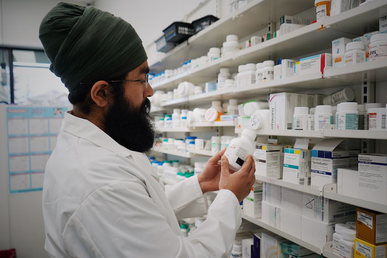 Pharmacist checking medicine expiry dates on pharmacy shelves