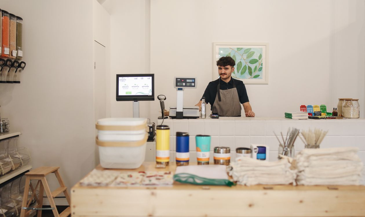 Cashier serving a customer at a retail counter during a busy trading hour