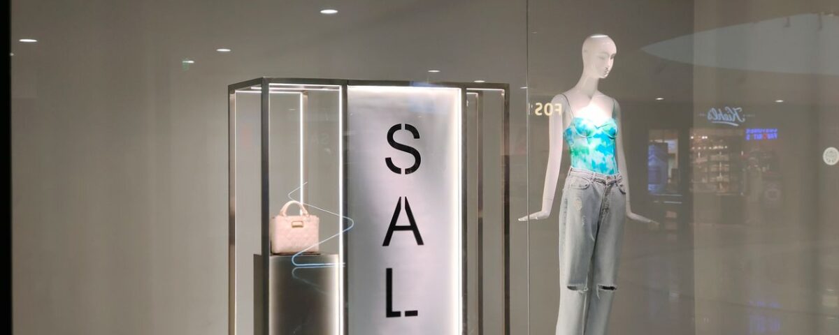 Clothing store window display with a seasonal sale sign