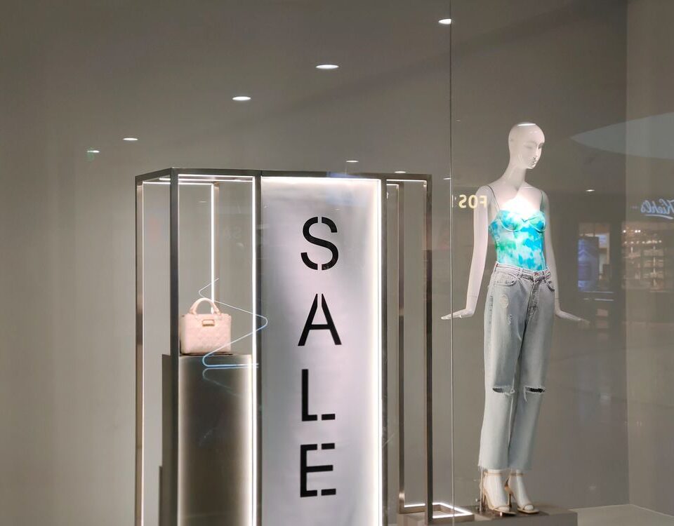 Clothing store window display with a seasonal sale sign