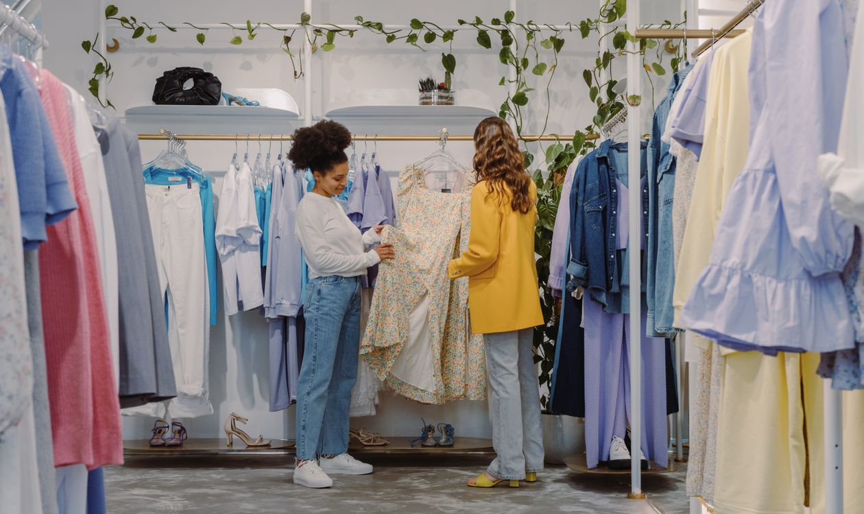 Customers browsing a clothing rack while choosing sizes in a boutique